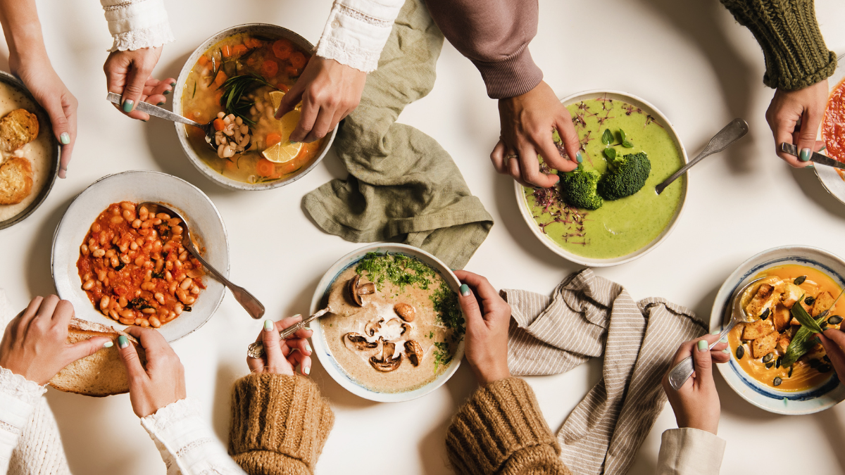 Several pairs of hands serve a variety of purees at a shared table