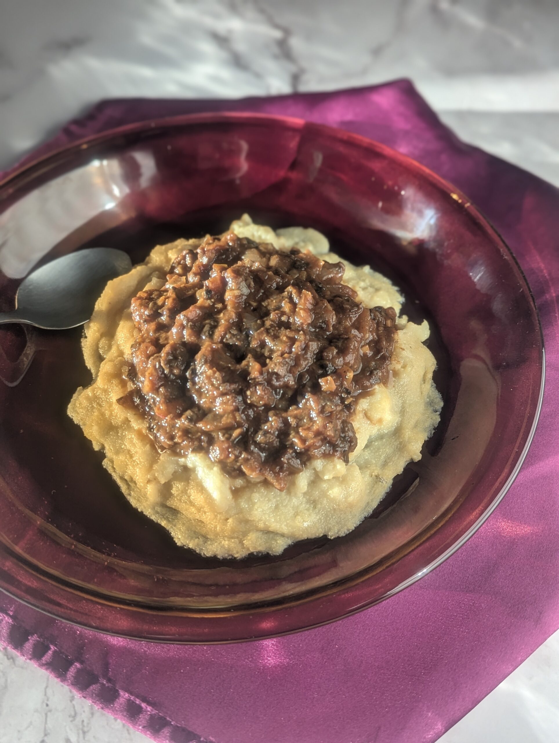 A plate of creamy parmesan polenta topped with mushroom ragu